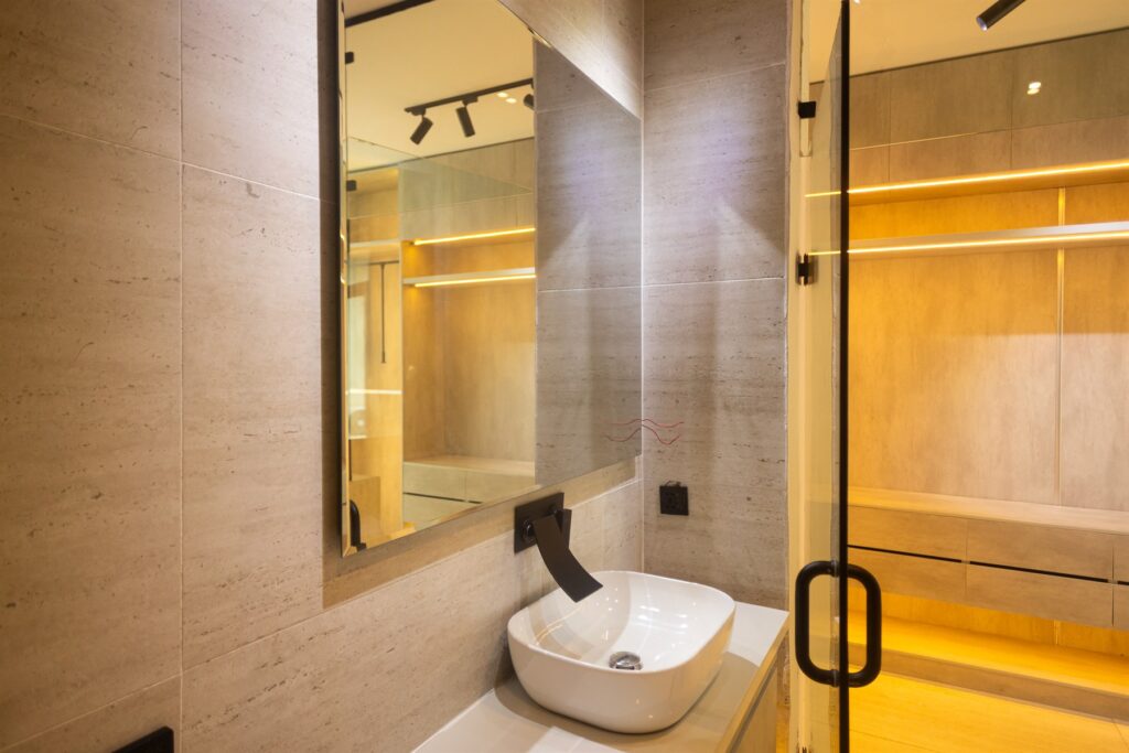 Brum Height 6: Vanity basin and mirror beside a glass shower partition